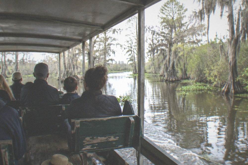 Families seated under the roof of a covered swamp boat watching the water