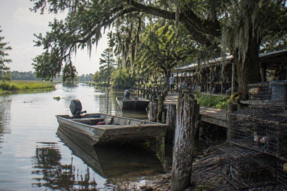 A small Louisiana town dock with fishing boats moored along a bayou lined with trees