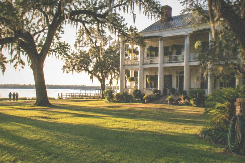 Antebellum plantation house with white columns viewed across a green lawn