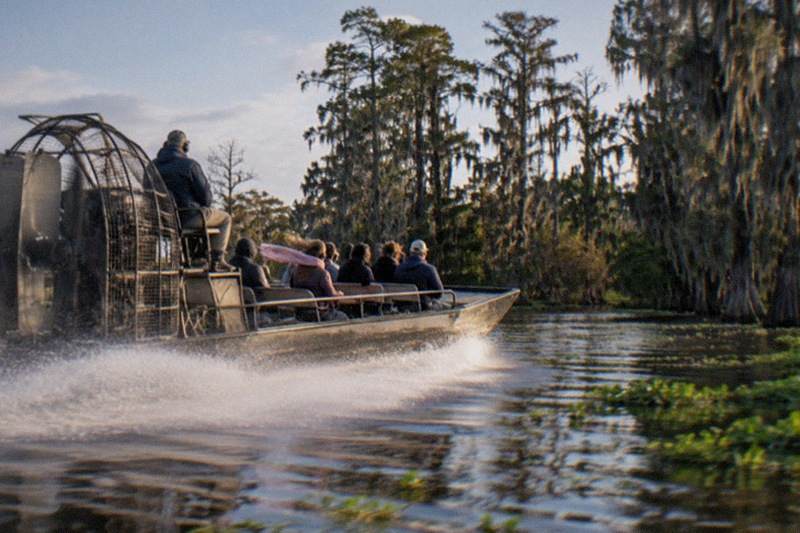 Airboat cutting open swamp water with spray off the hull