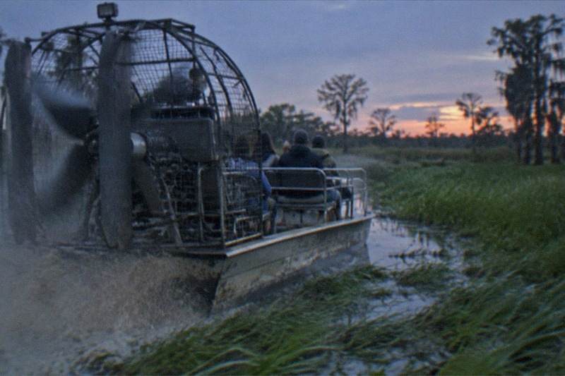Airboat speeding down a grassy channel in the Jean Lafitte swamp near New Orleans