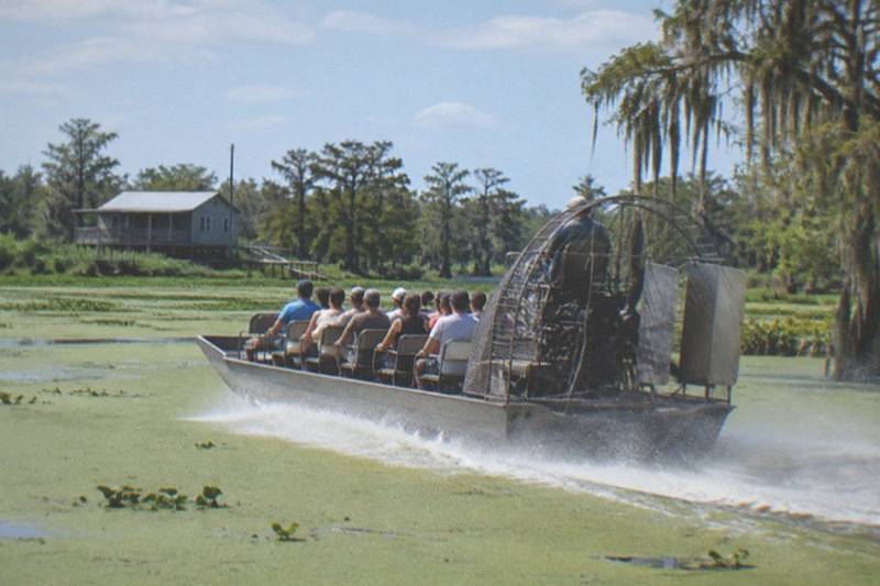 Sixteen-passenger airboat running across open Louisiana swamp water