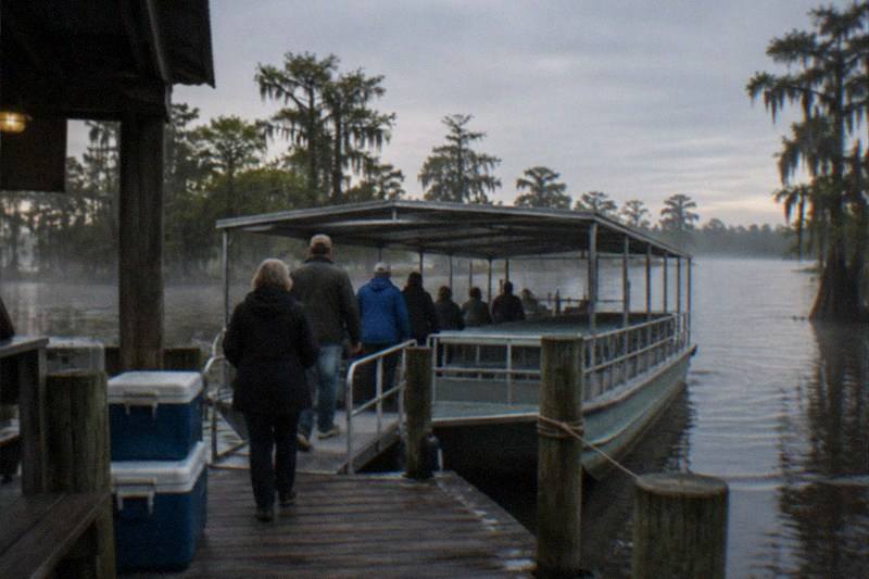Swamp cruise boat at a dock while passengers board for a bayou tour